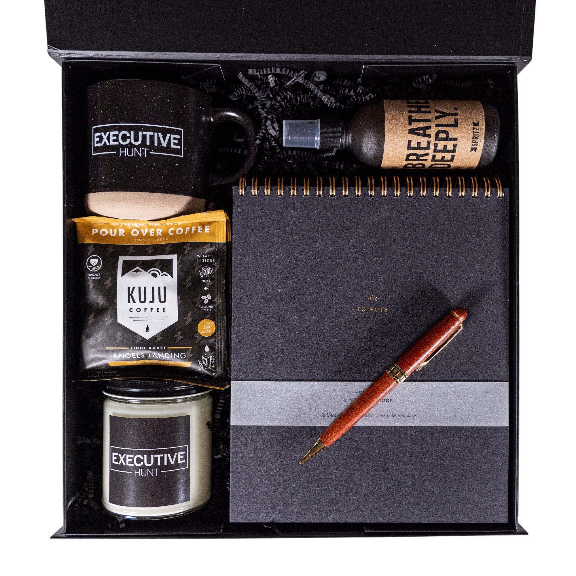 Corporate gift set with a branded mug, notebook, pen, coffee package, and customized candle in a black box.